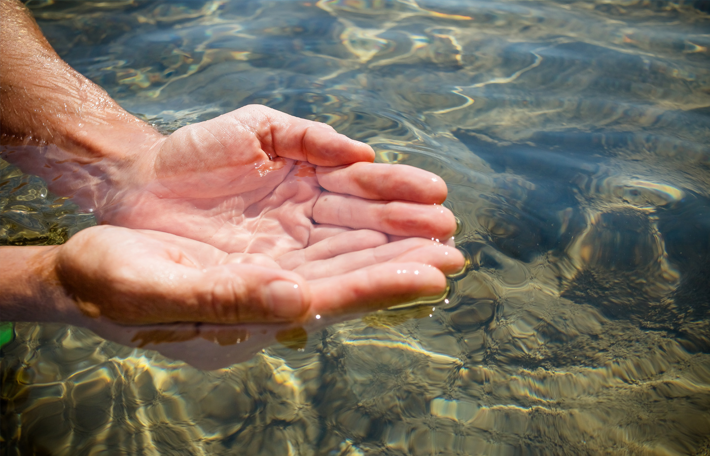 Image of hands in clear sea water.